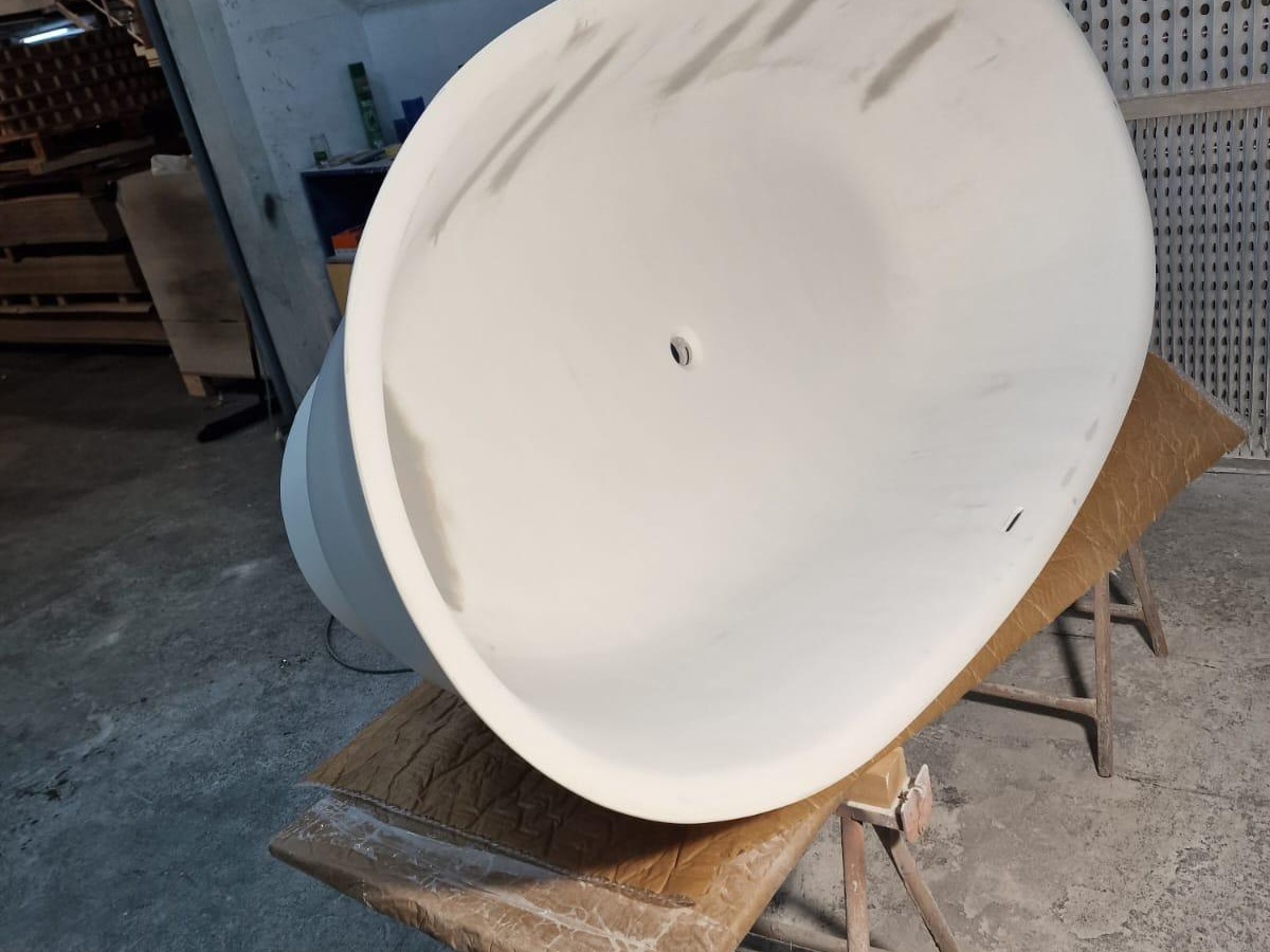 Vista lateral de la bañera exenta impresa en 3D durante el pintado — acabado blanco mate corporativo LAUFEN