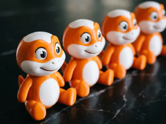 Serie de figuras de mascota corporativa impresas en 3D en naranja y blanco — merchandising de marca personalizado