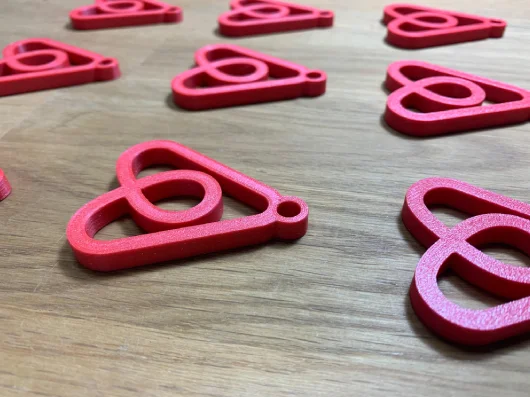 Llaveros con logo impresos en 3D en rojo — merchandising corporativo y regalos de empresa